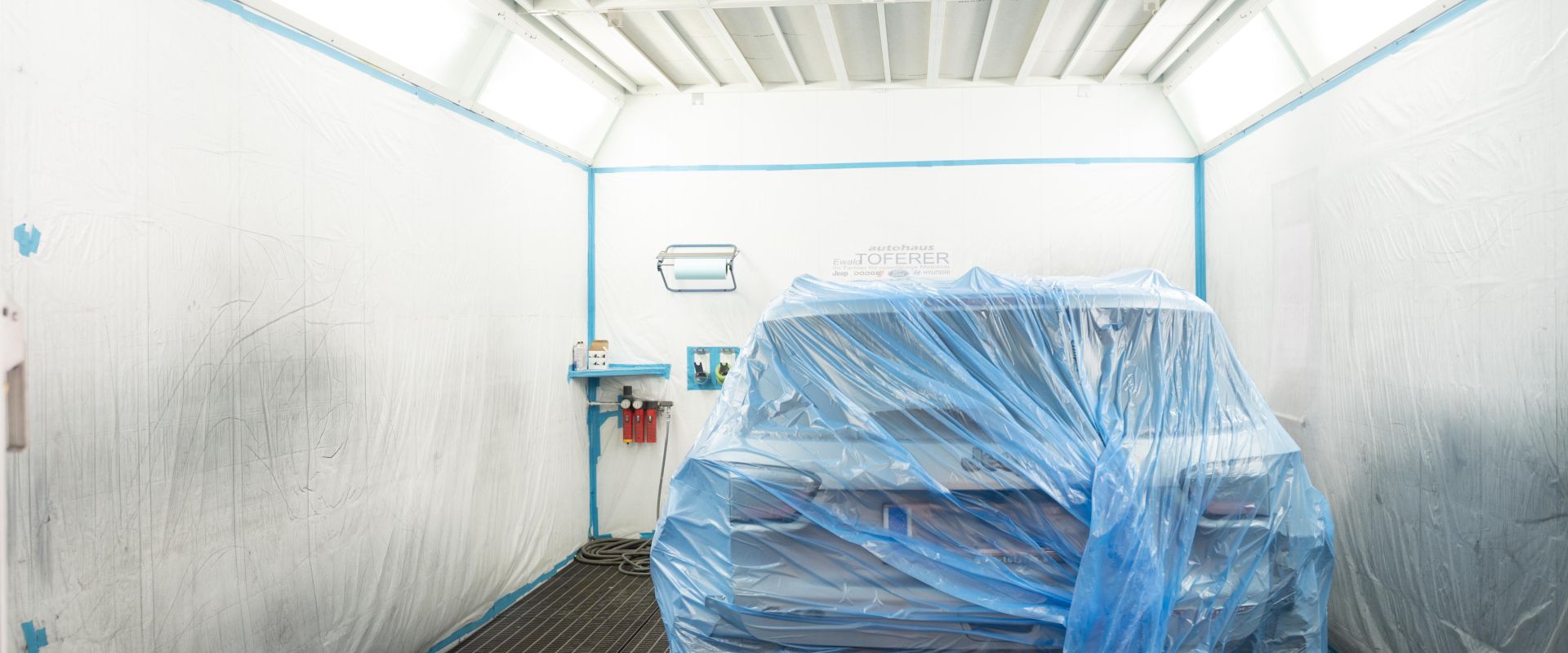Lackierungsraum, in dem ein Auto eingehüllt in plastik ist